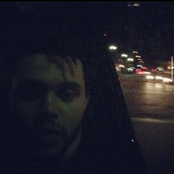 a man sitting in the back seat of a car at night with traffic behind him