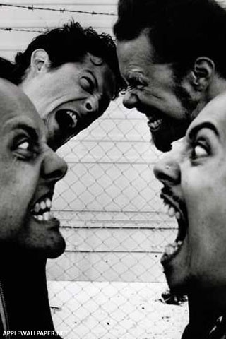 four men with their mouths open in front of a chain link fence