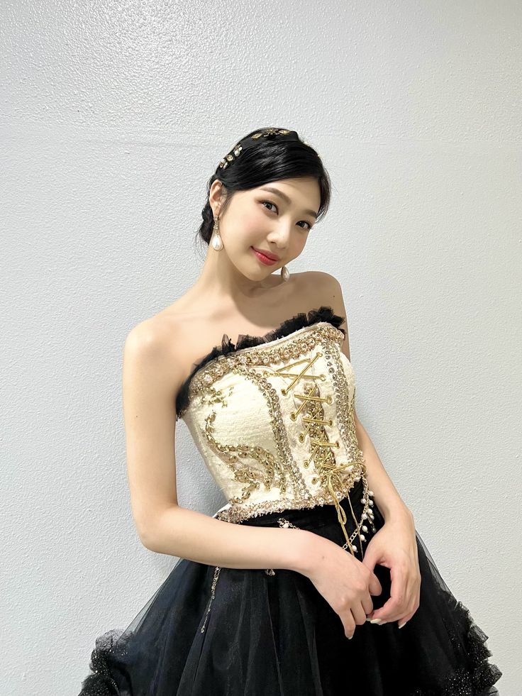 a woman in a black and gold dress posing for the camera with her hand on her hip