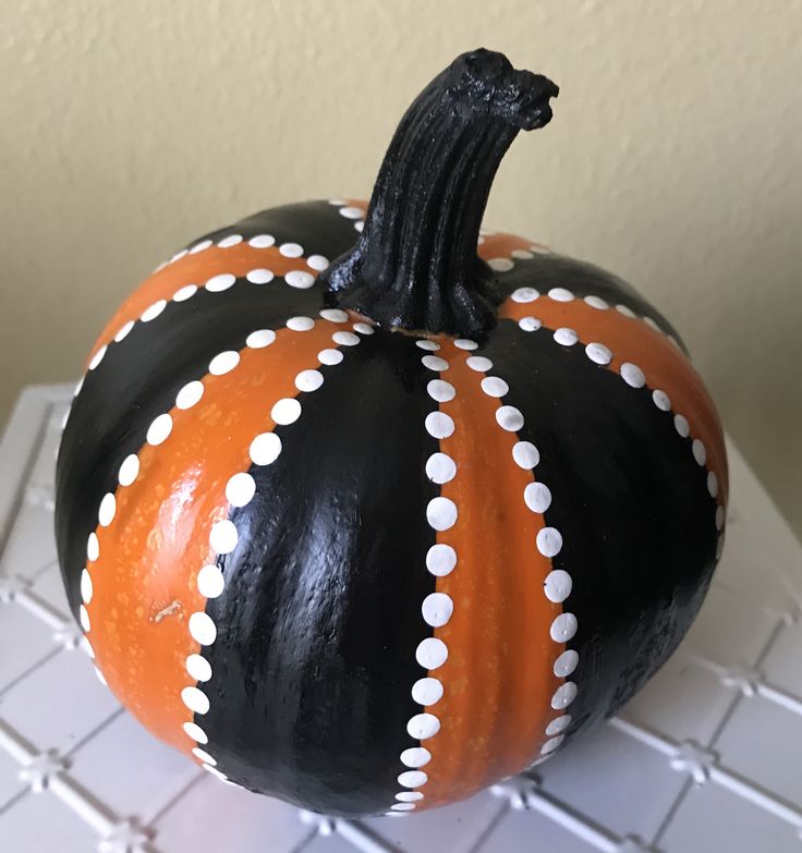 a black and orange painted pumpkin sitting on top of a white tiled counter next to a wall