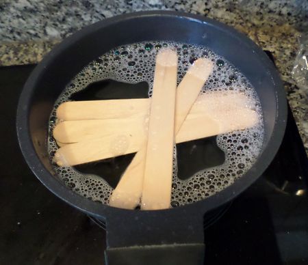 popsicles are being cooked in a frying pan with water on the stove top