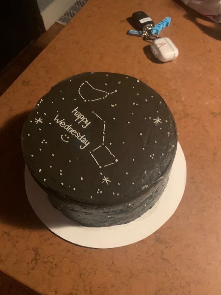 a black cake with white stars on it sitting on a table next to a mouse