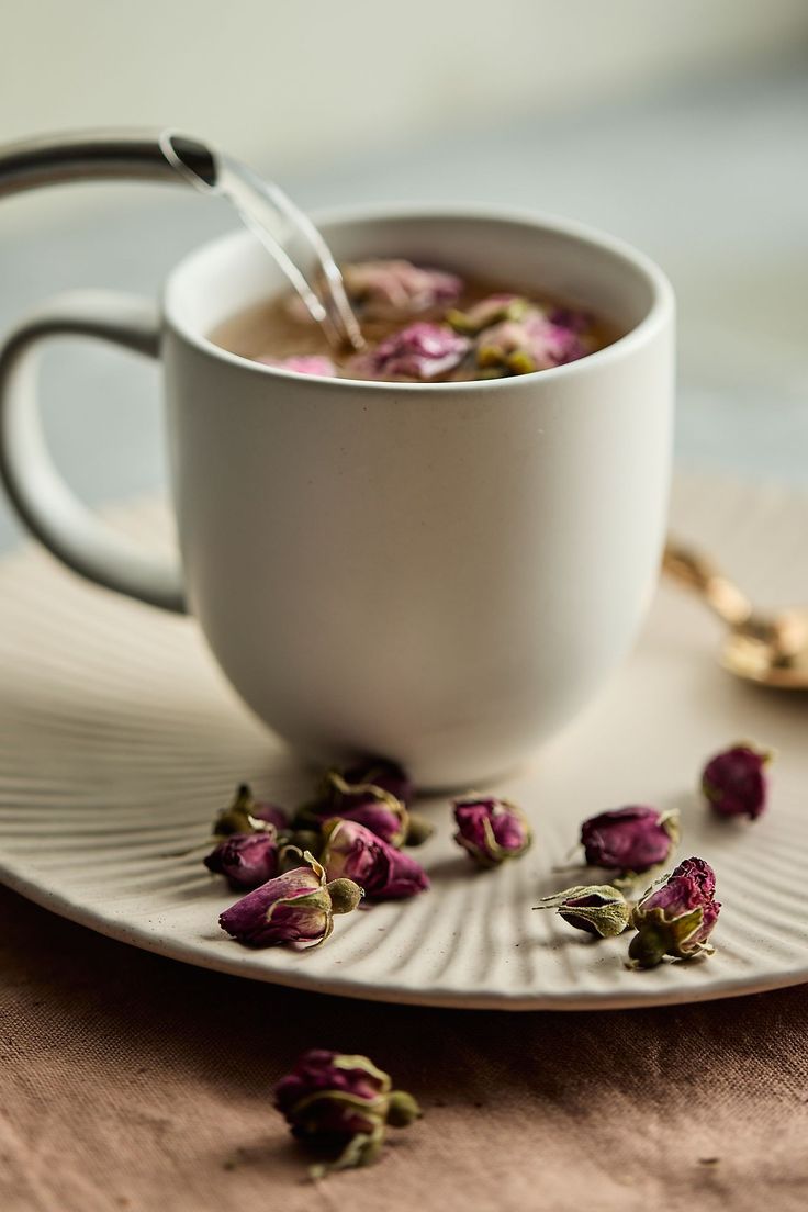 a cup of tea with rose petals on a saucer