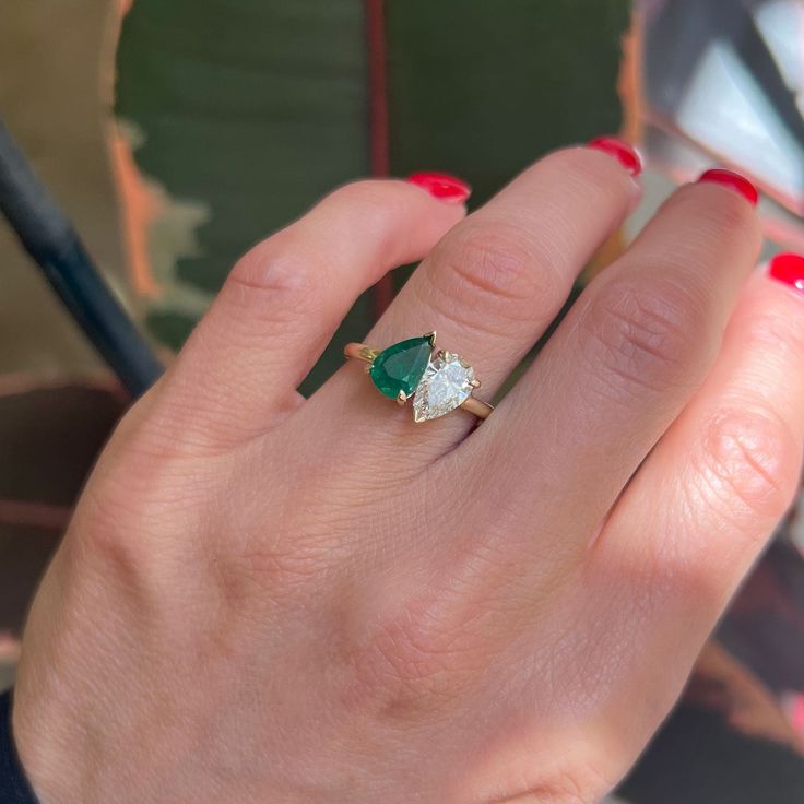 a woman's hand with a green and white diamond ring on her left hand