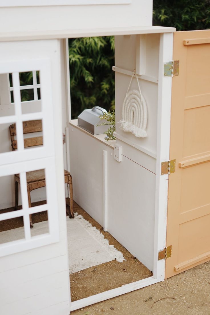 an open door to a doll house with furniture in it's doorway and outside