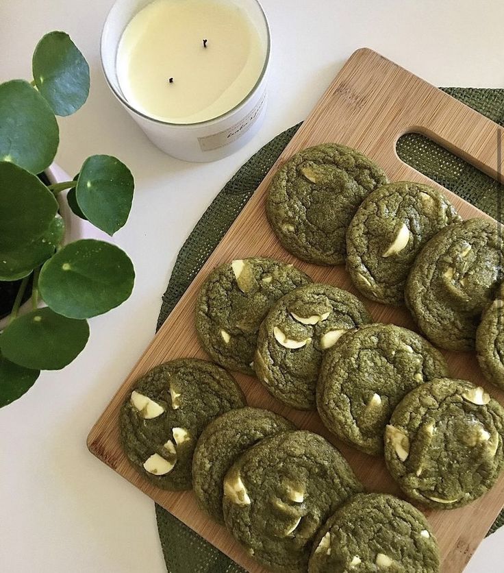 cookies are on a cutting board next to a glass of milk and a potted plant