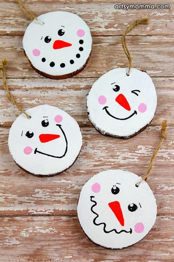 three snowman ornaments hanging from string on wooden table