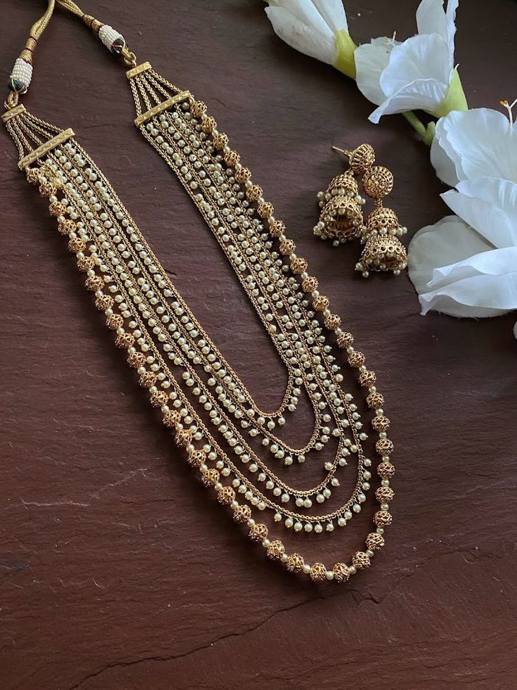 24 K gold plated beaded long necklace with matching delicate earrings Highest quality and craftsmanship Indian Bridal Traditional One Gram Jewelry Necklace Set. Length : 22 inches  All the raw material used in this product is of high quality and is handcrafted with love. Premium Quality and High craftsmanship 100% Satisfaction Guarantee: Long Lasting Plating, High-Quality Stones. Gifting: This pair of charming necklace and earrings come in a beautiful gift box, making it an ideal gift for birthd Luxury Long Beaded Necklace With Gold Beads, Luxury Gold Bollywood Mala, Gold Kundan Chandbali Necklace With Dangling Beads, Gold Chandbali Kundan Necklace With Dangling Beads, Gold Long Kundan Necklace For Party, Gold Temple Jewelry Chain Necklace For Wedding, Gold Long Kundan Necklace For Festive Occasions, Traditional Gold Chain Necklace For Wedding, Festive Gold Long Kundan Necklace