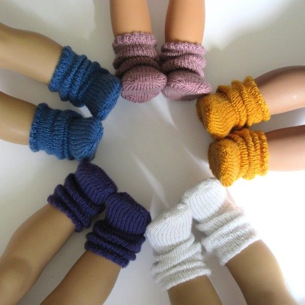 several different colored knitted finger puppets arranged in a circle on a white table top