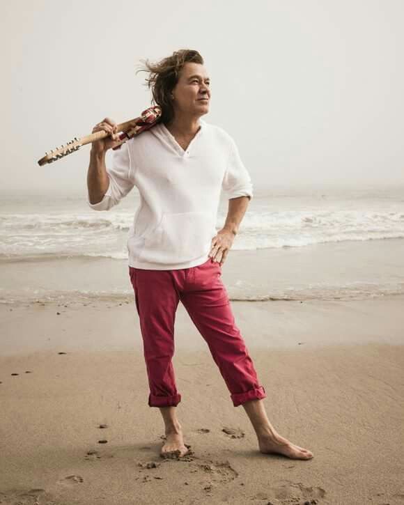 a man standing on top of a beach next to the ocean holding a baseball bat