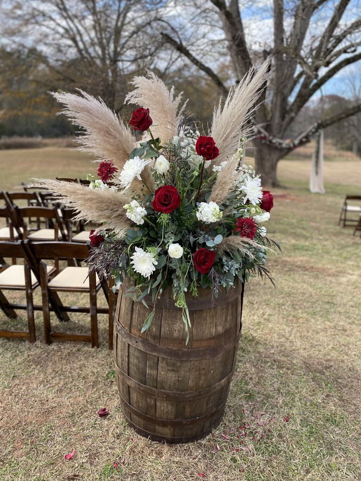 a wooden barrel with flowers and feathers on the ground in front of rows of chairs