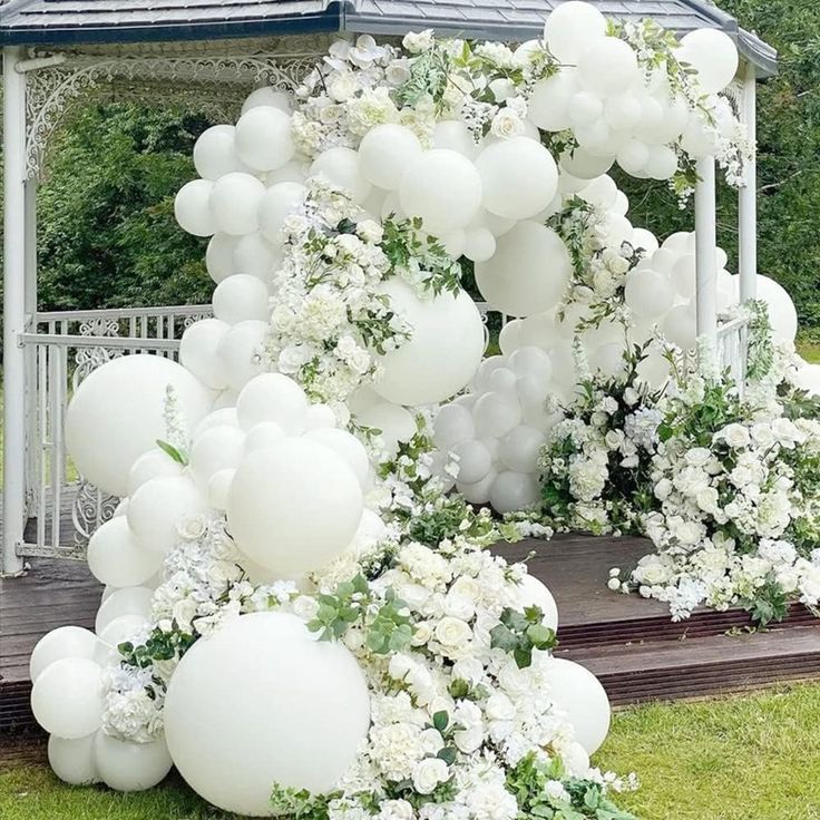 a gazebo decorated with white balloons and flowers