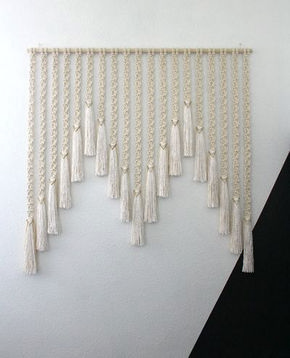 a white wall hanging with tassels on it and the words photo above it