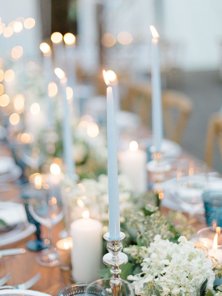 the table is set with candles, flowers and silverware for an elegant dinner party