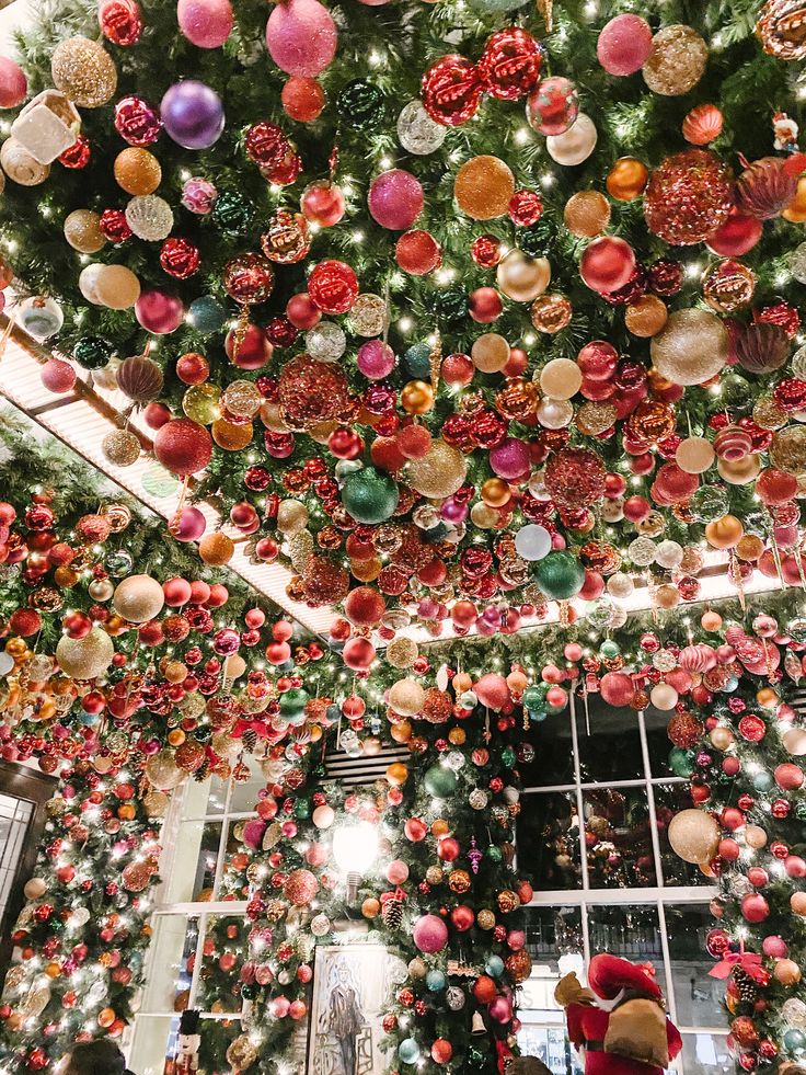 christmas decorations hanging from the ceiling in a room filled with trees and other holiday items