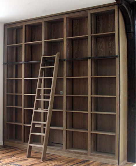 an empty bookcase with ladder leaning against it