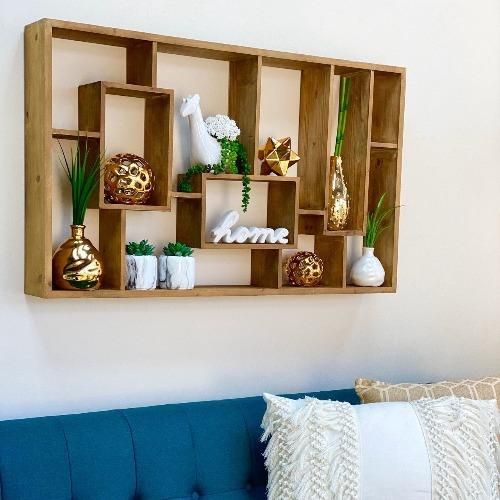 a blue couch sitting in front of a wooden shelf filled with vases and plants