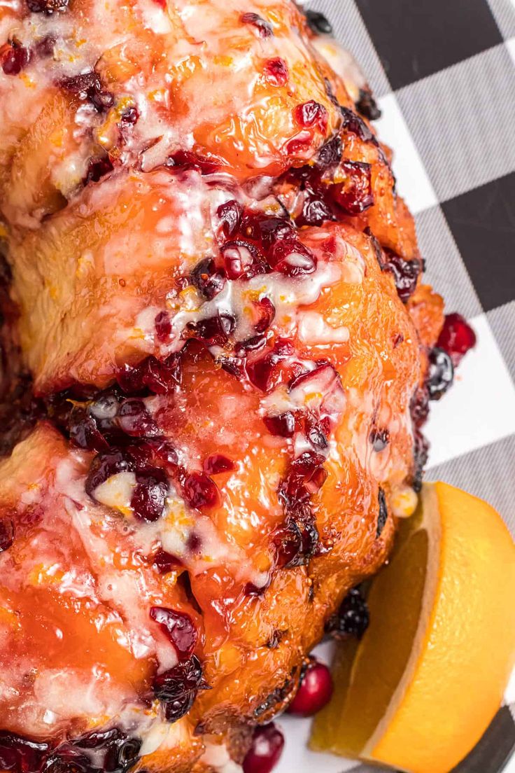 a close up of a chicken on a plate with cranberries and oranges