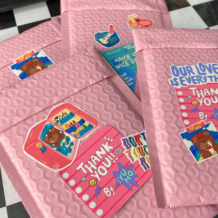 four pink thank you notes are on a checkerboard floor with black and white tiles