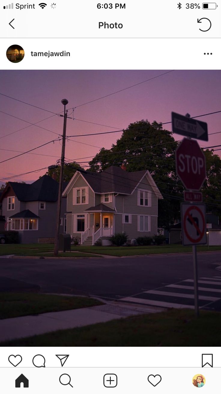 a stop sign in front of some houses at dusk with the sun setting behind them