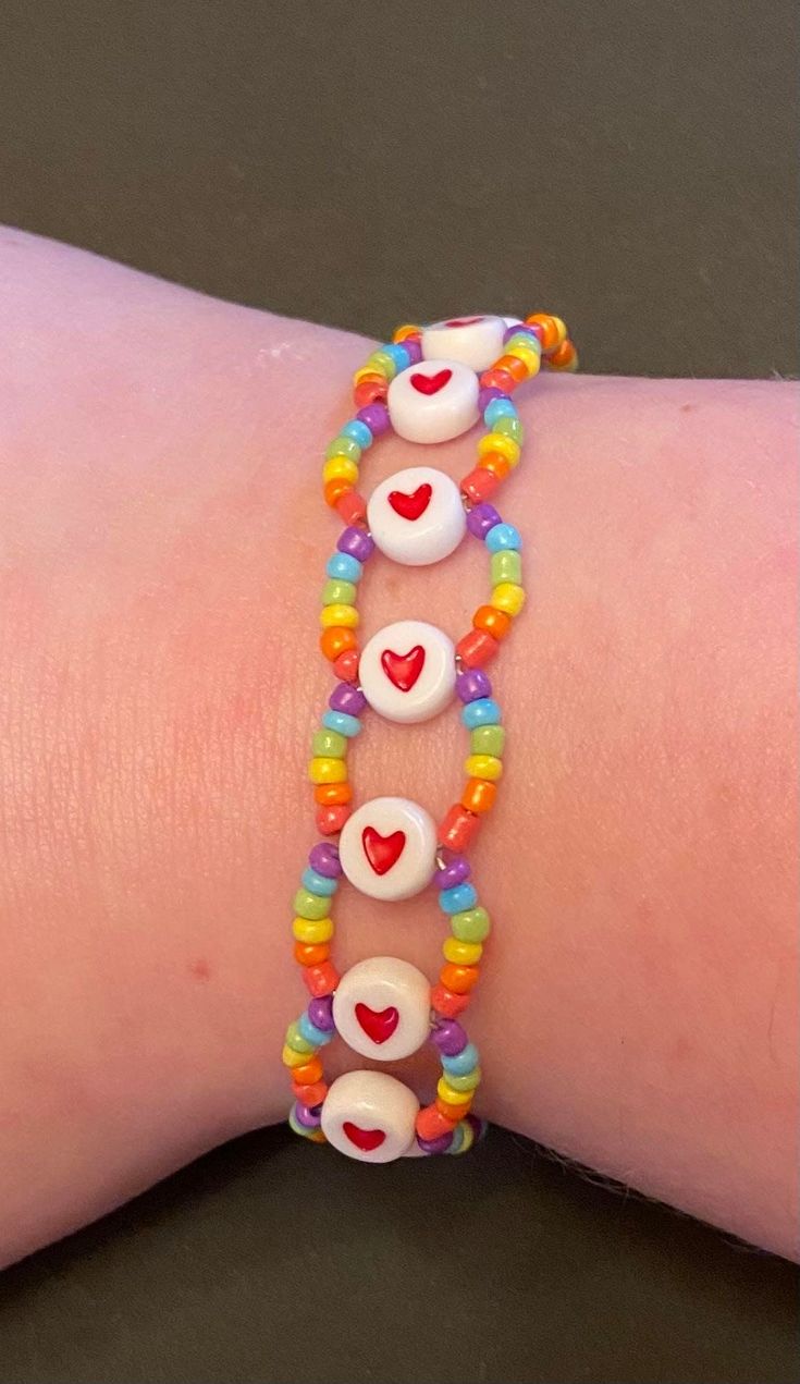 the bracelet is decorated with colorful beads and heart shaped charms on it's wrist