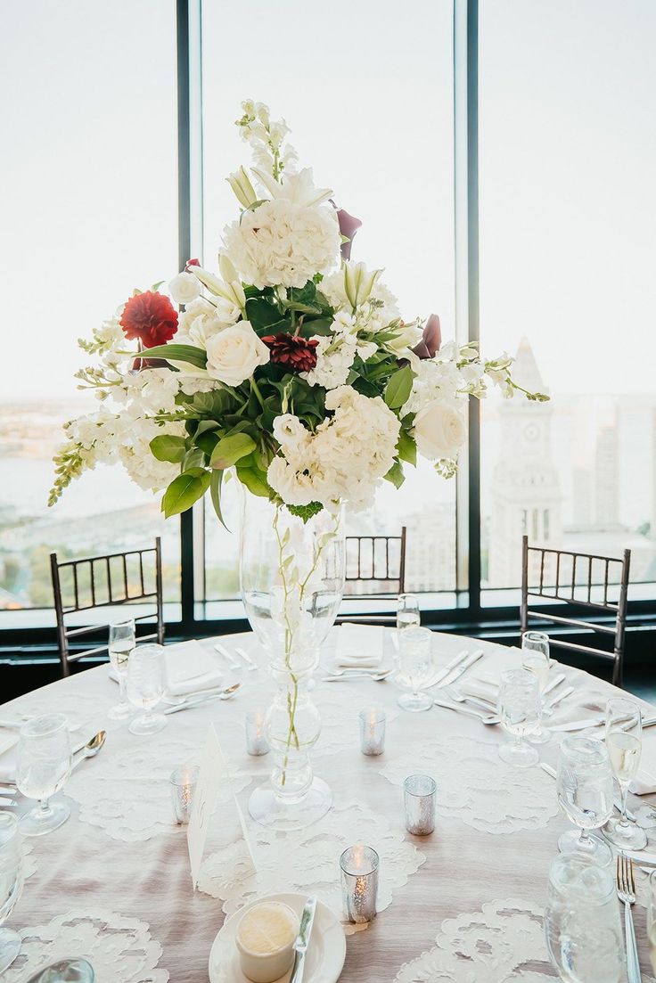 a vase filled with white and red flowers on top of a table next to candles