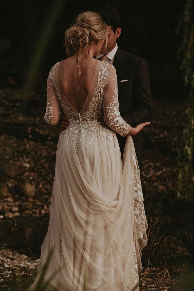 a bride and groom standing in the woods looking at each other with their back to the camera