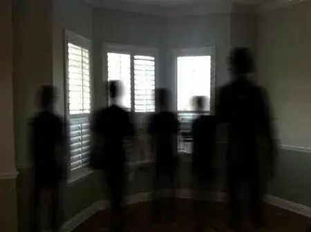 blurry image of people standing in front of windows with blinds on the window sill