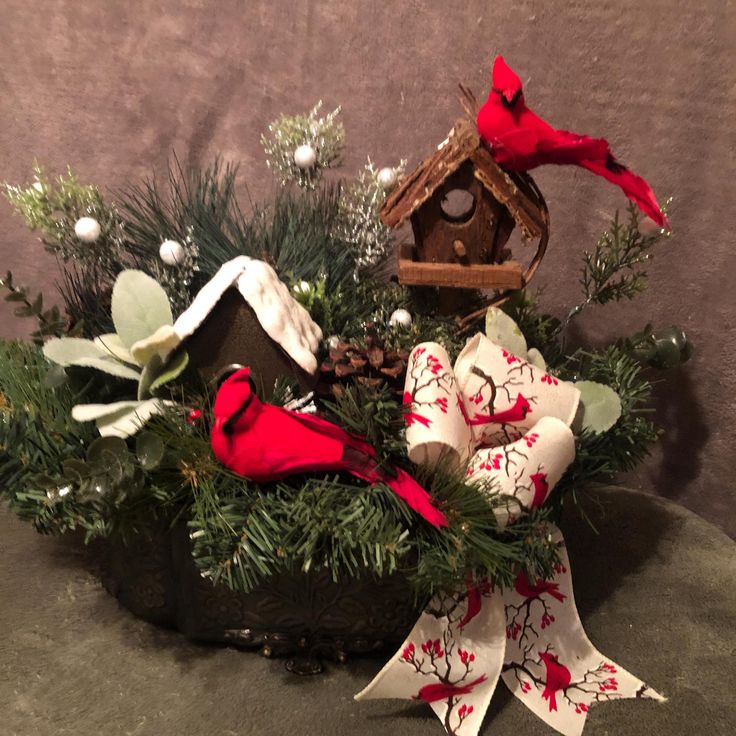 a christmas arrangement with red birds and pine cones