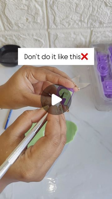 a person is cutting paper with scissors on a white table and purple plastic containers are in the background