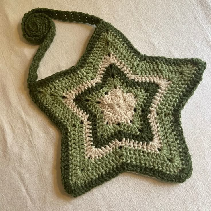 a crocheted green and white star ornament on a white surface with a string