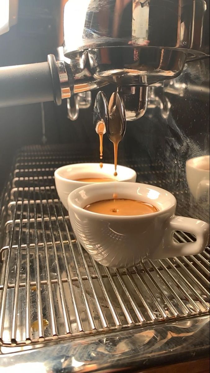 a cup of coffee being poured into the espresso machine