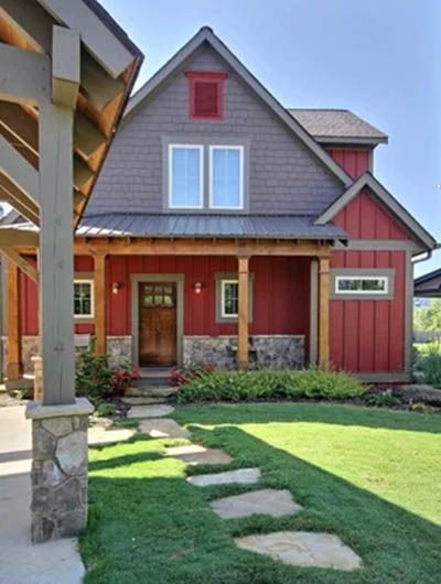 a red house with stone steps leading to the front door and covered porchs on either side