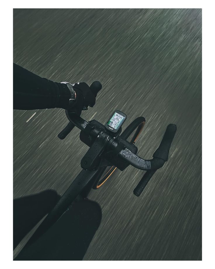 a person riding a bike in the rain with their phone attached to the handlebars