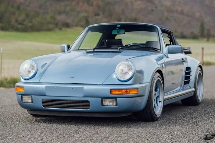 a blue sports car parked on the side of a road next to a green field