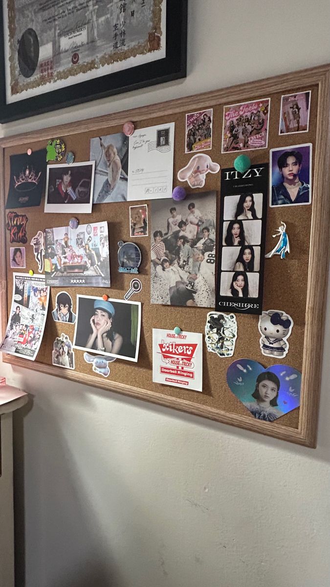 a bulletin board with pictures and magnets on it next to a desk in a room