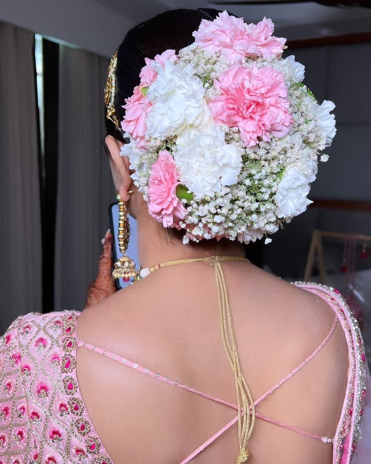 the back of a woman's head with pink and white flowers in her hair