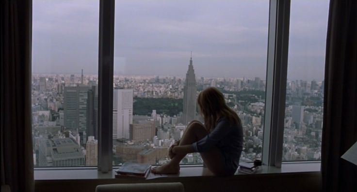 a person sitting in front of a window with a view of the city and skyscrapers