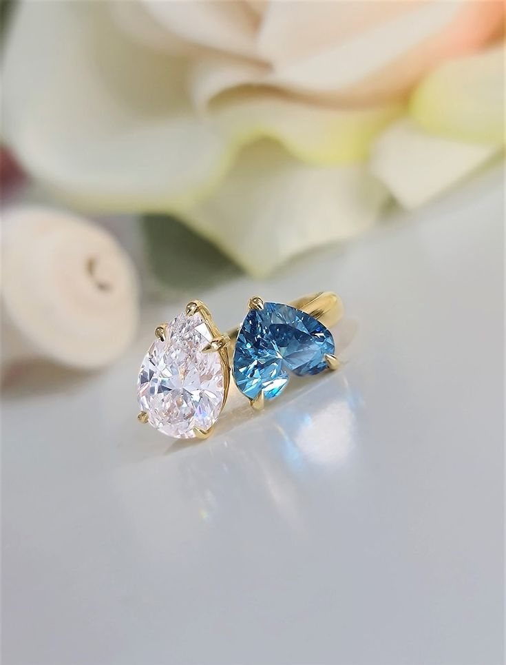 two blue and white diamond rings sitting next to each other on top of a table