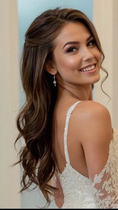 a woman with long hair wearing a wedding dress and smiling at the camera while standing in front of a mirror