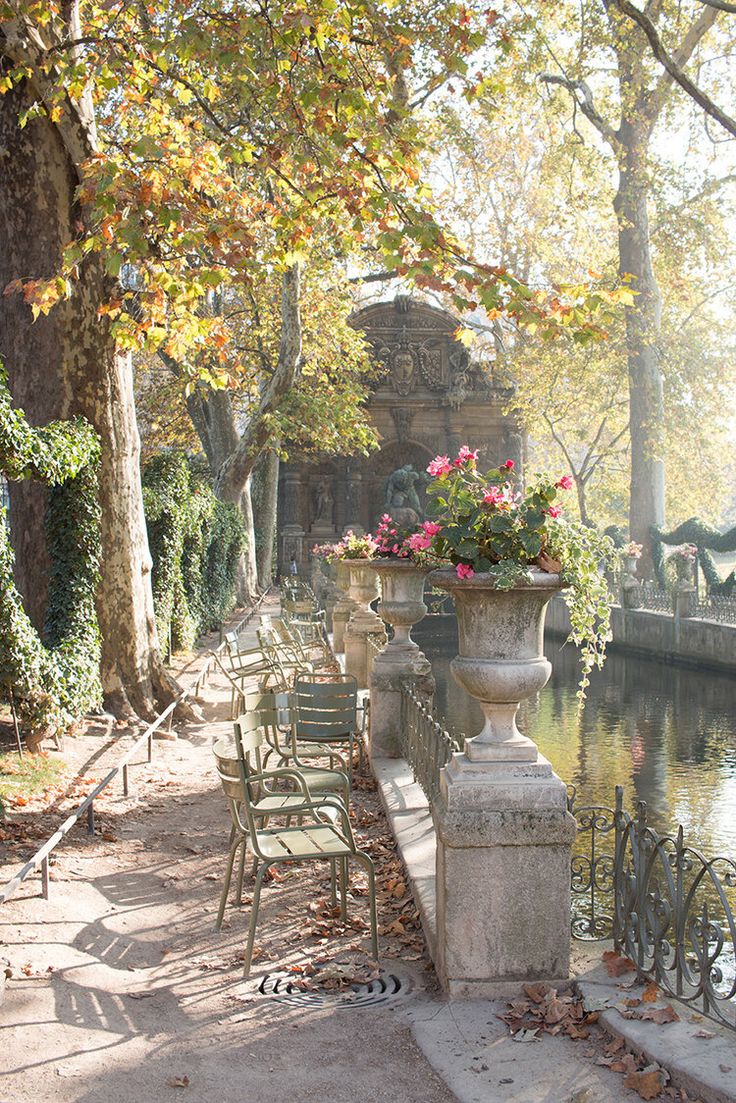 there are many chairs and tables along the water's edge with flowers in them