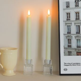 three lit candles sitting on top of a table next to a cup and book cover