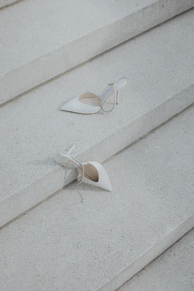 two pairs of white shoes sitting on top of cement steps with one pair broken off