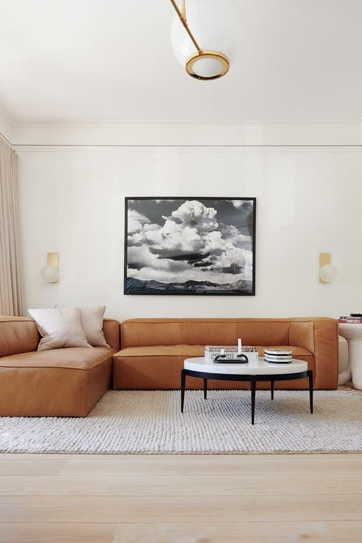 a living room with a couch, coffee table and painting on the wall above it