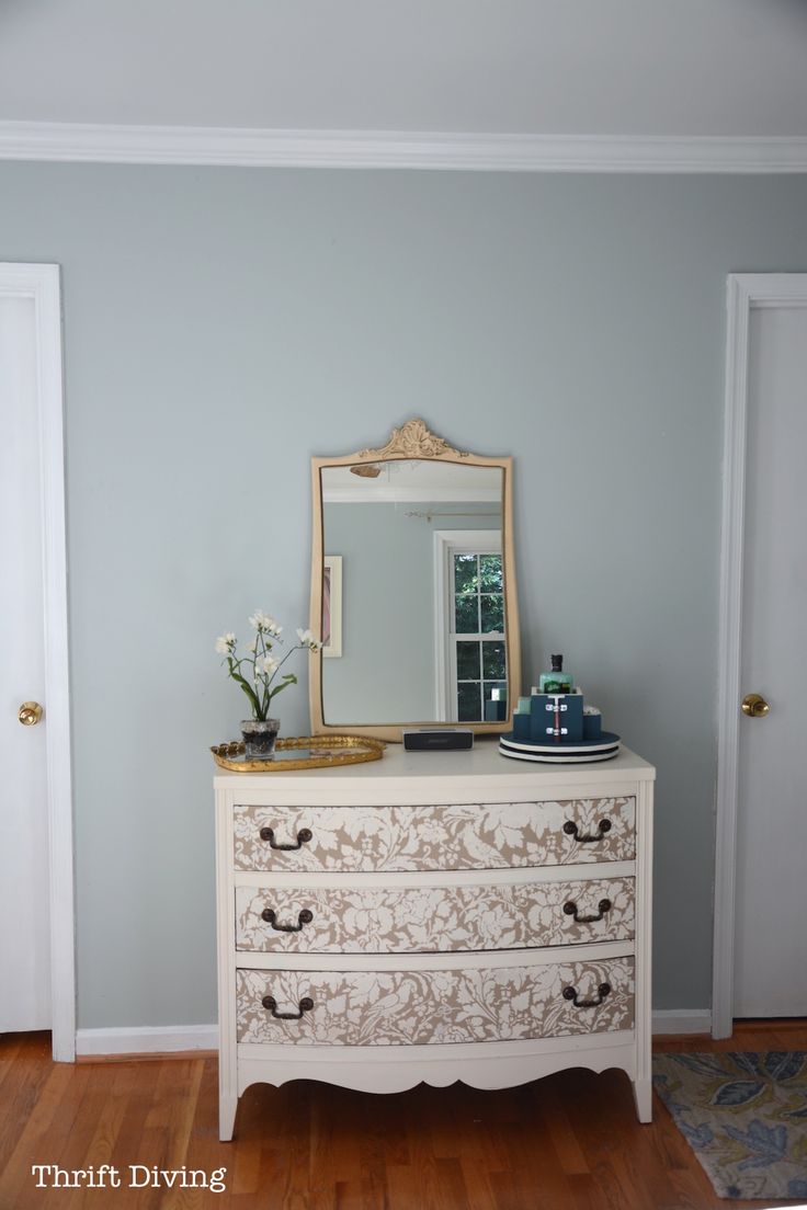 a white dresser with a mirror on top of it