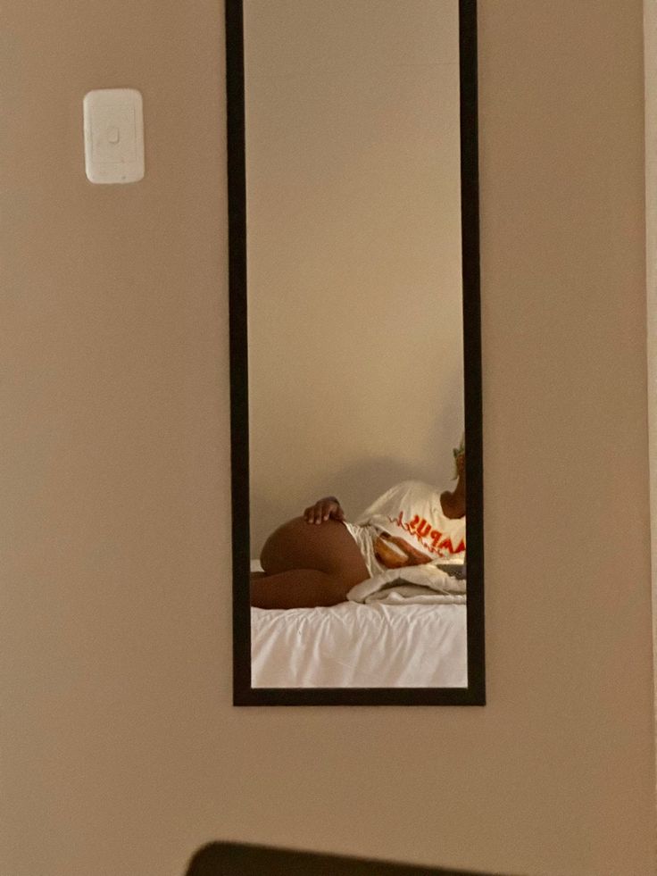 a woman laying on top of a bed in front of a mirror