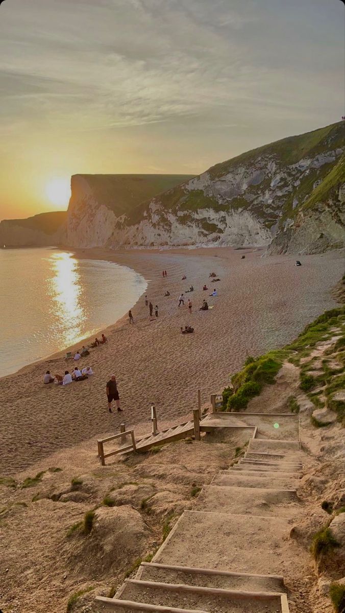 stairs lead down to the beach as people walk on the sand and in the water