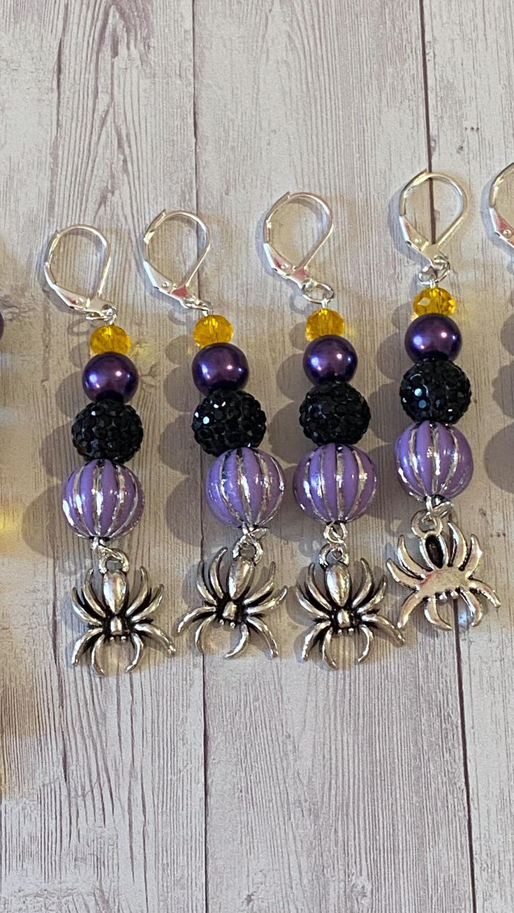 six pairs of beaded key chains on a white wooden surface with beads and charms attached to them