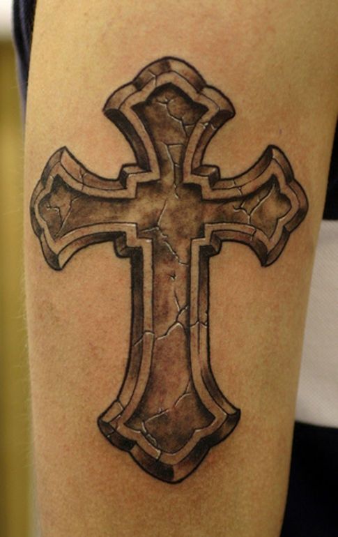 a cross tattoo on the leg of a person's arm, which is black and grey