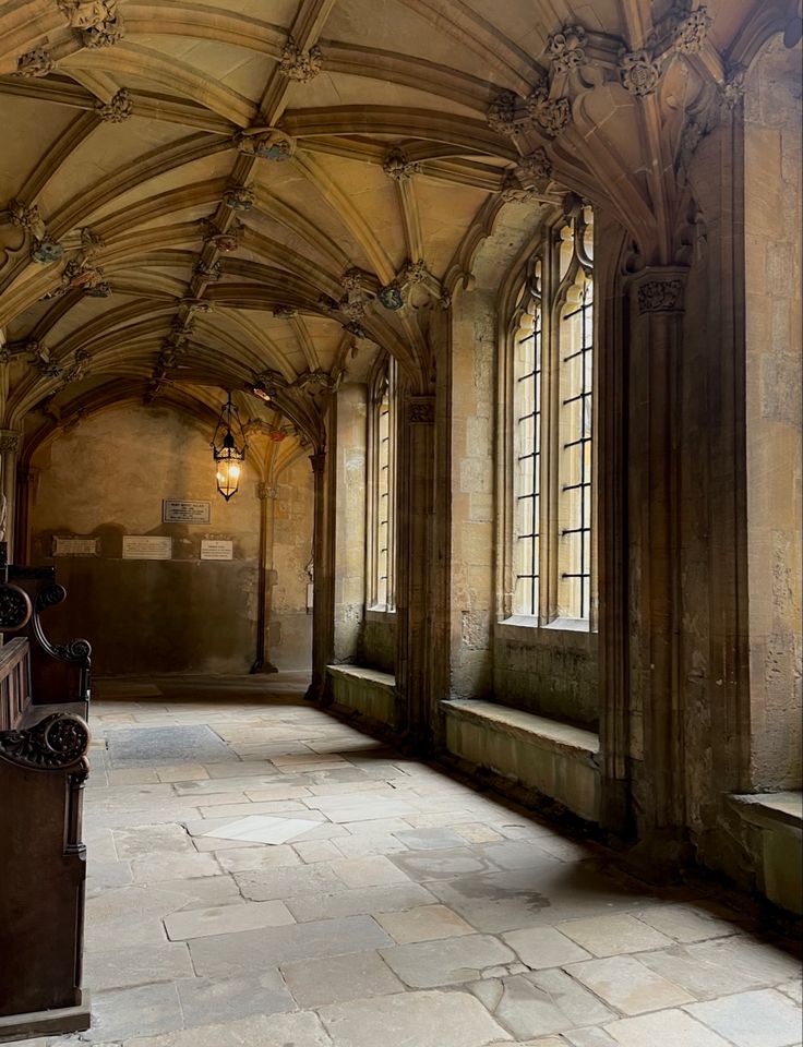 an old building with stone floors and arched windows, along with a bench in the middle